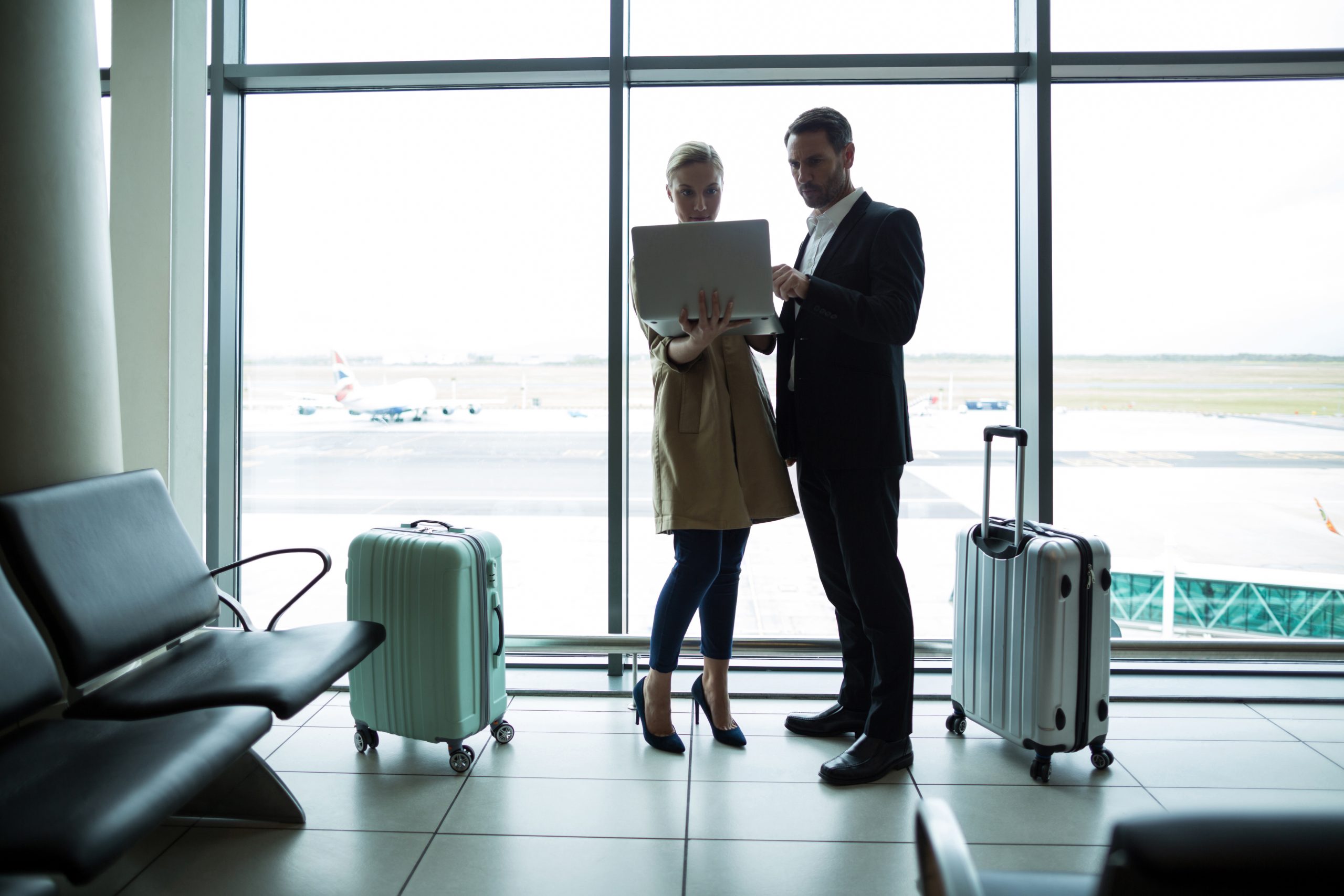 businesspeople discussing over laptop at airport